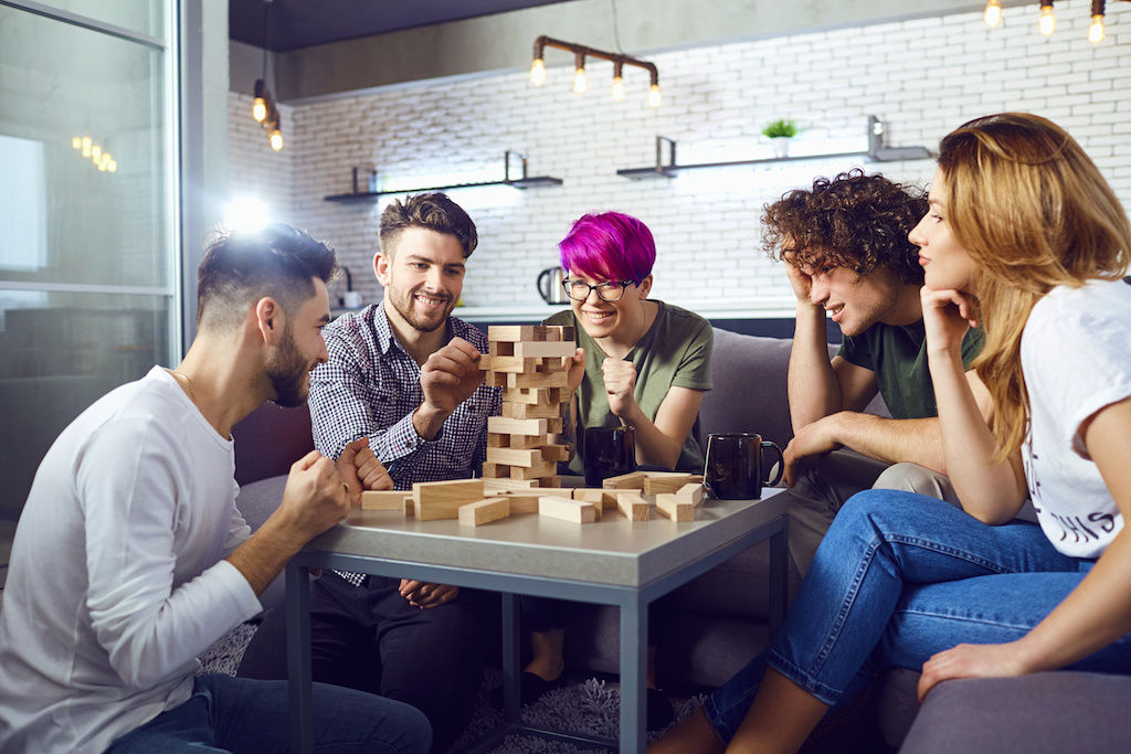 Friends gathered around table playing Jenga